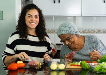 Candid Moment of Latina Woman Cooking with Elderly Afro Grandmother at Home