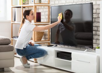 Woman Wiping The Television Screen At Home
